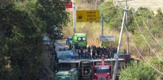 A flipped bus on a highway with ambulances