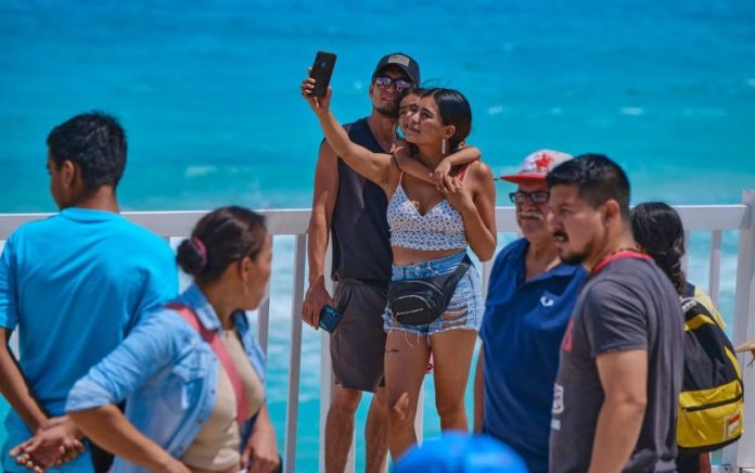 A tourist takes a selfie on a beach in Quintana Roo
