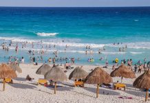 People enjoy the sand and sea on the beach in Tulum