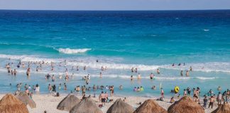 People enjoy the sand and sea on the beach in Tulum