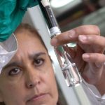 Woman looks at water in a test tube