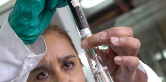 Woman looks at water in a test tube