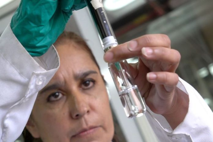 Woman looks at water in a test tube