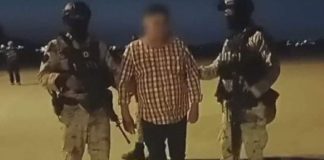 Two officers hold the suspect, Abraham Oseguera