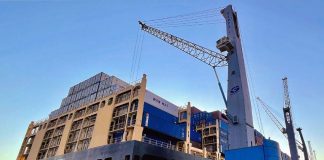 A cargo ship docked in Mexico with a crane preparing to remove containers containing trade goods from China.