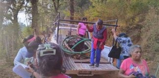 Elderly women carrying pumps and hoses into a pickup truck in rural Michoacan