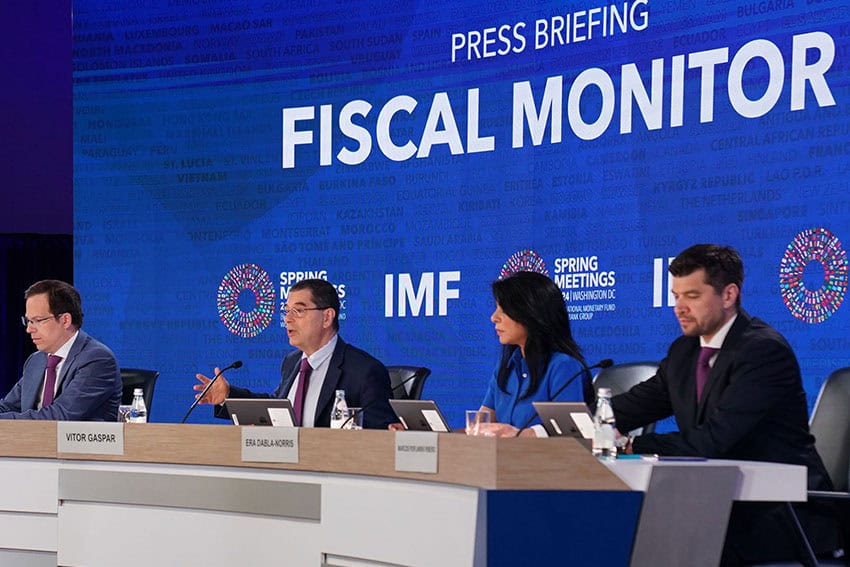 Four members of the IMF sitting at a conference table during a press briefing