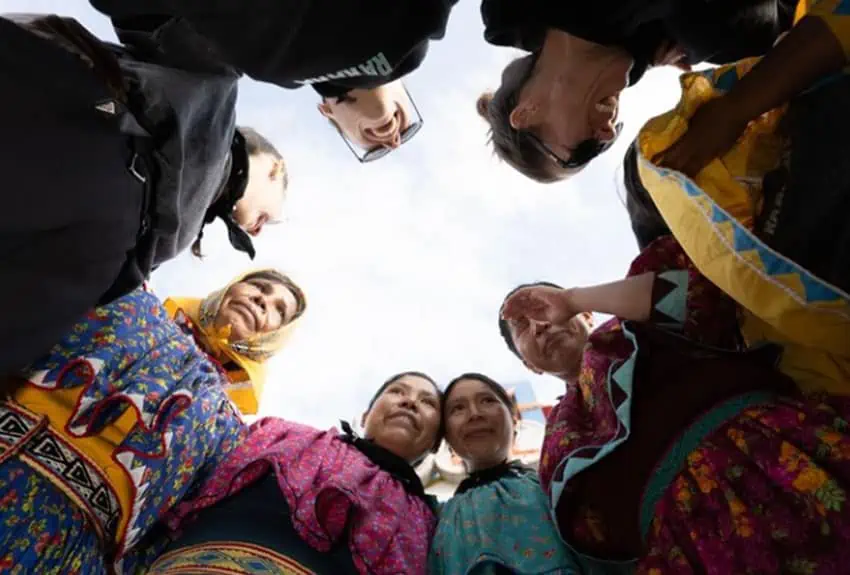 A Rararmuri indigenous team of women in traditional dress in a sports huddle.