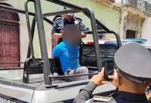 Photo of suspect seated handcuffed in police truck bed with a blurred out head