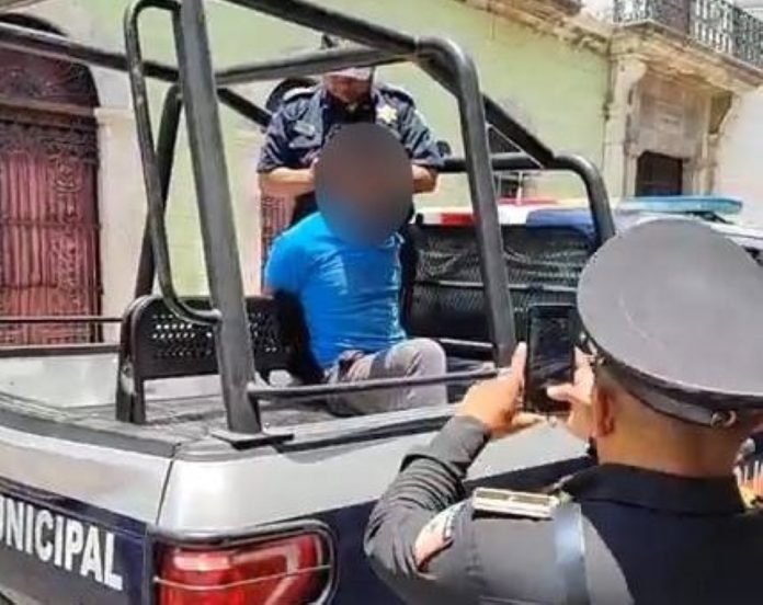 Photo of suspect seated handcuffed in police truck bed with a blurred out head