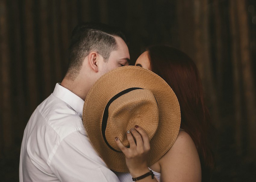 Couple kissing behind a hat