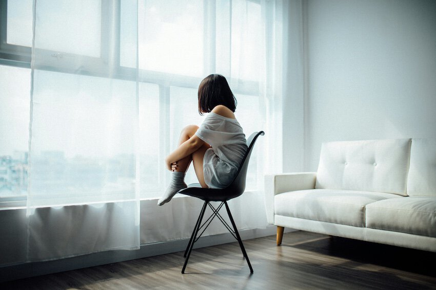 Woman staring out the window sitting on a chair waiting