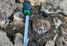 A mayan stone sculpture of a face, on the ground at a archeological dig in Chumpón, Mexico