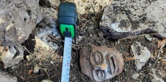 A mayan stone sculpture of a face, on the ground at a archeological dig in Chumpón, Mexico