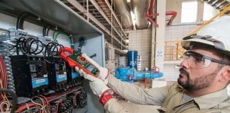 A Mexican electrician holding a digital monitor in front of a geothermal system