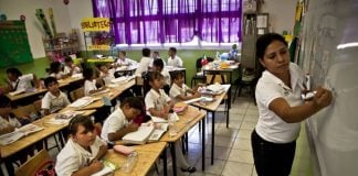 A teacher stands in front of a classroom of students in a Mexican school.