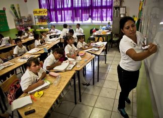 A teacher stands in front of a classroom of students in a Mexican school.