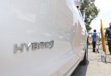 A close up view of a white hybrid car with the word hybrid on the passenger's side door