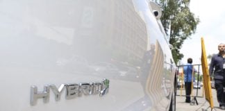 A close up view of a white hybrid car with the word hybrid on the passenger's side door