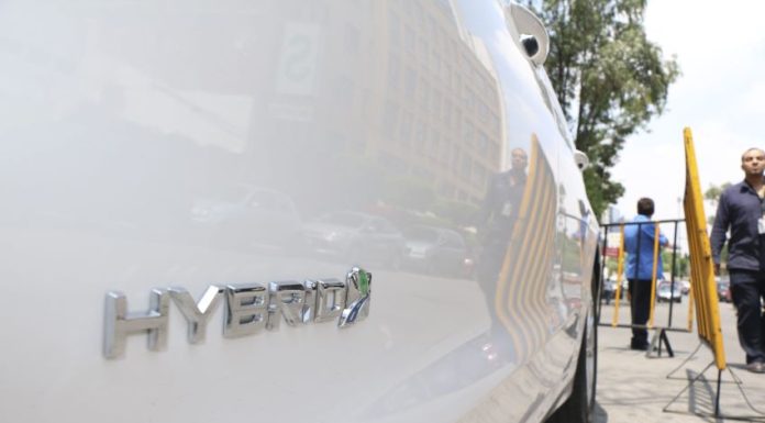 A close up view of a white hybrid car with the word hybrid on the passenger's side door