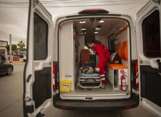 An EMT loads a person on a stretcher into an ambulance.