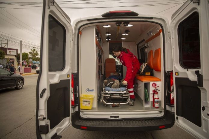 An EMT loads a person on a stretcher into an ambulance.