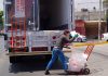 A worker loads bags of ice onto a cart.