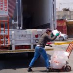 A worker loads bags of ice onto a cart.