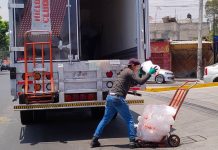 A worker loads bags of ice onto a cart.