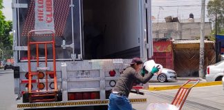 A worker loads bags of ice onto a cart.