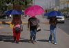Three women shield themselves with umbrellas during a heat wave in Mexico.