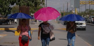 Three women shield themselves with umbrellas during a heat wave in Mexico.