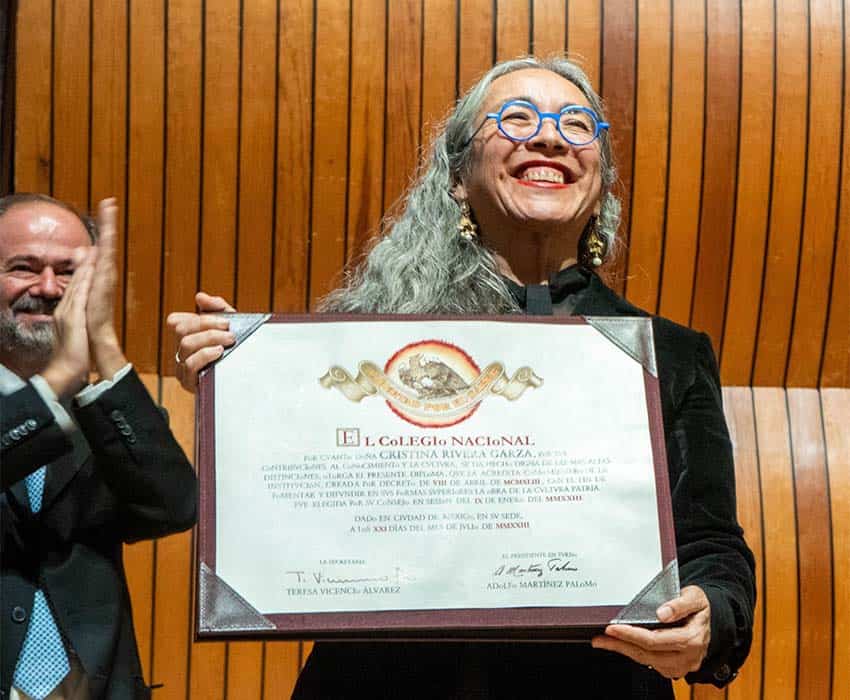 Cristina Rivera Garza onstage displaying certificate of membership after induction into Mexico's Colegio Nacional