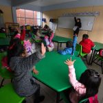 Children raise their hands in a Mexican classroom