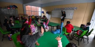 Children raise their hands in a Mexican classroom