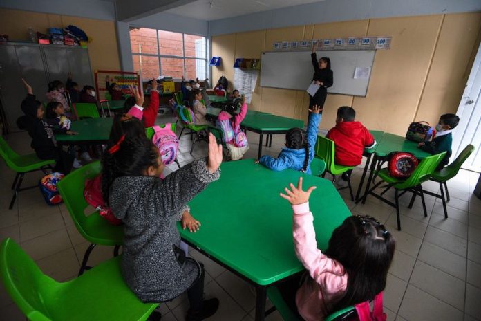 Children raise their hands in a Mexican classroom