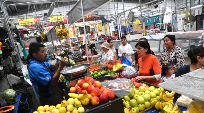 Vendor and customers at a fruit and vegetable market stall
