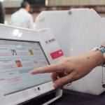 A Mexican citizen presses a button on an official voting machine.
