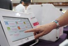 A Mexican citizen presses a button on an official voting machine.
