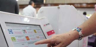 A Mexican citizen presses a button on an official voting machine.