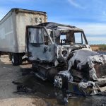 A truck that is burned out on a highway