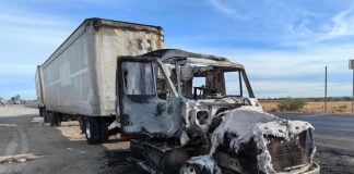 A truck that is burned out on a highway