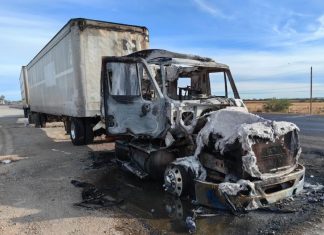 A truck that is burned out on a highway