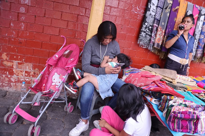 A Mexican mother feeds her baby at a roadside stall