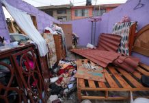 A house with the roof torn of by the tornado, leaving water damage to the bed, dresser and clothes.