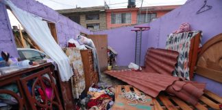 A house with the roof torn of by the tornado, leaving water damage to the bed, dresser and clothes.
