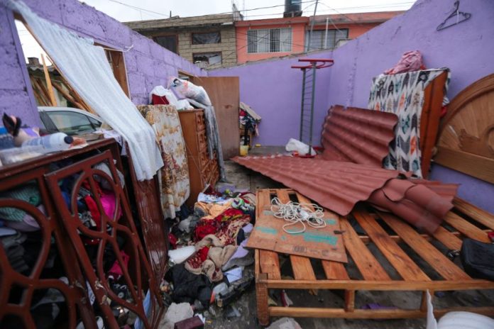 A house with the roof torn of by the tornado, leaving water damage to the bed, dresser and clothes.