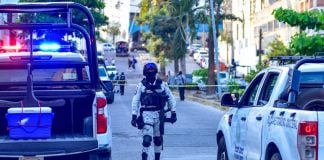 A National Guard agent stands between two police vehicles on a cordoned-off street outside of El Pueblito market in Acapulco, Guerrero,.