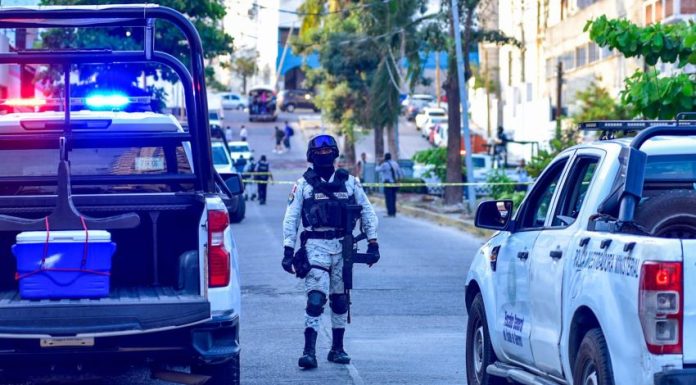 A National Guard agent stands between two police vehicles on a cordoned-off street outside of El Pueblito market in Acapulco, Guerrero,.
