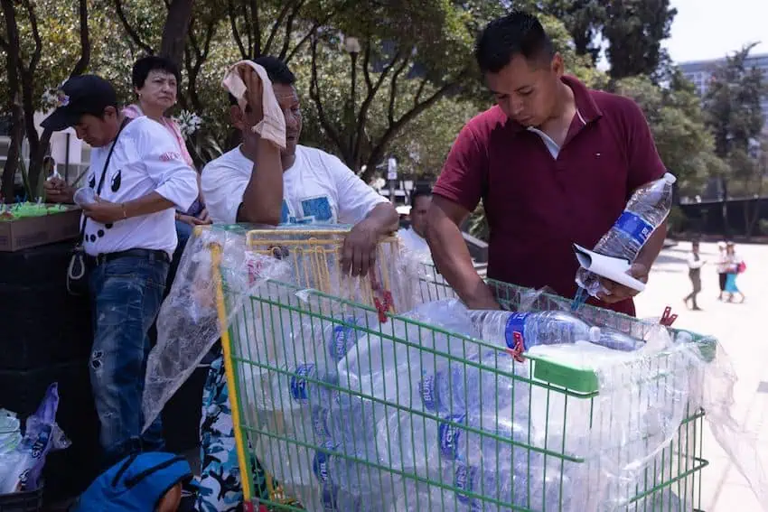 People take water bottles from a shopping cart on an extremely hot day in Mexico City